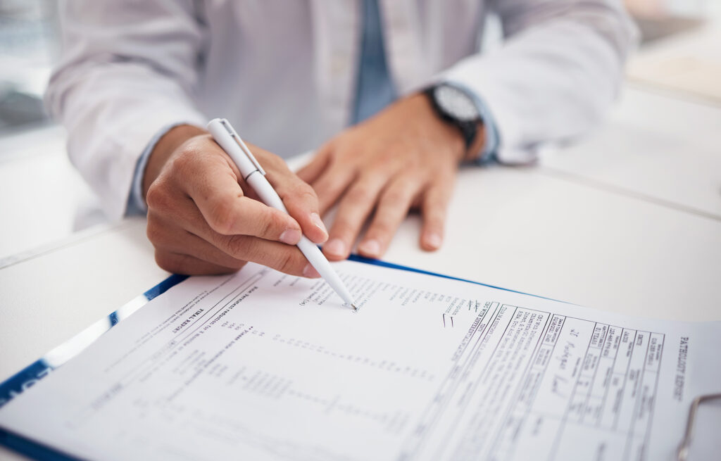 Closeup, doctor and hands with document for writing on insurance form, information or chart of patient for treatment. Healthcare professional, nurse or specialist with clipboard for medical history.