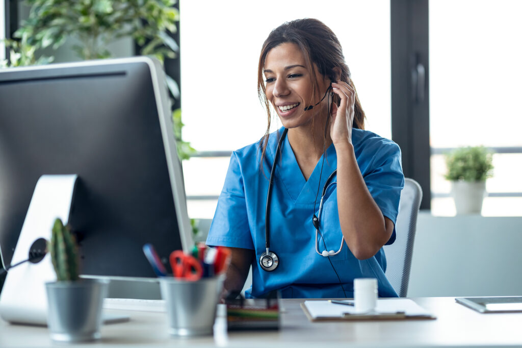 Shot of female doctor talking with earphone while explaining medical treatment to patient through a video call with computer in the consultation.